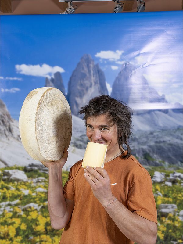 Alpinist Simon Gietl holding a wheel of cheese
