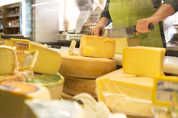 Mani che tagliano il formaggio al banco
