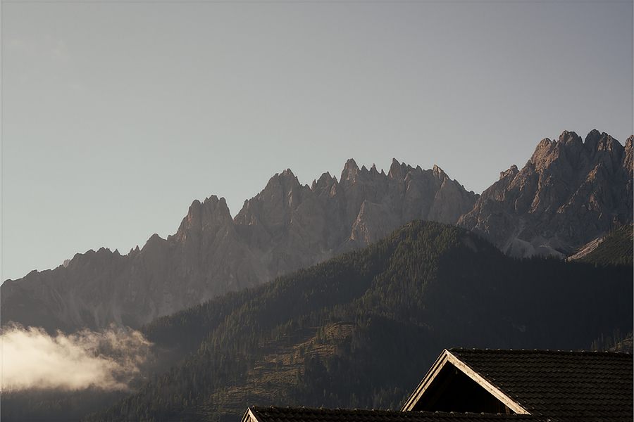 Il tetto di un maso davanti alle Dolomiti nella nebbia del mattino